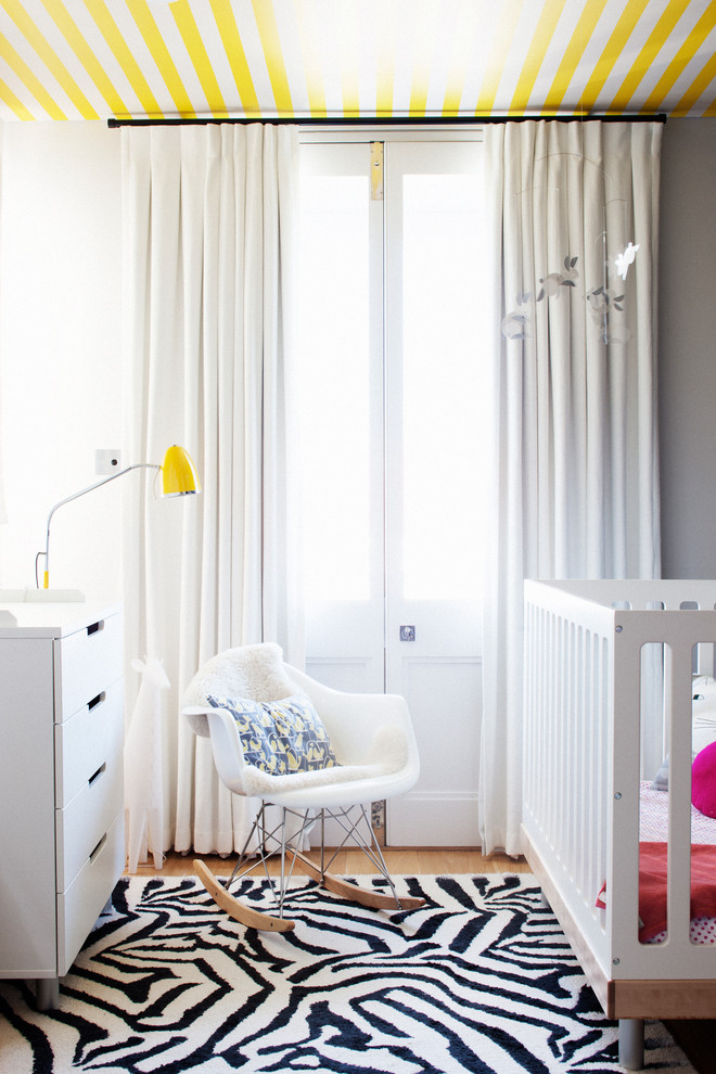 This is an example of a small contemporary gender-neutral nursery in Sydney with grey walls and light hardwood floors.