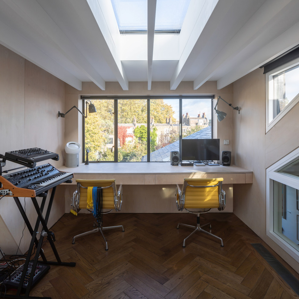 Diseño de estudio actual de tamaño medio con suelo de madera en tonos medios, escritorio empotrado, suelo marrón, vigas vistas y madera