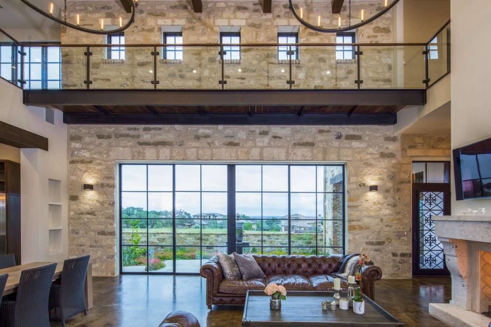 Photo of a large mediterranean formal open concept living room in Austin with white walls, concrete floors, brown floor, a standard fireplace, a stone fireplace surround and a wall-mounted tv.