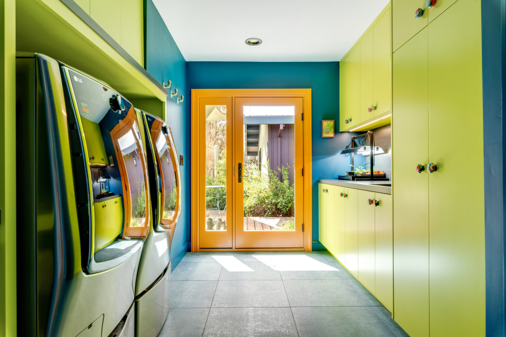 Inspiration för stora eklektiska grått tvättstugor enbart för tvätt, med en undermonterad diskho, släta luckor, gröna skåp, bänkskiva i kvartsit, grått stänkskydd, blå väggar, klinkergolv i keramik, en tvättmaskin och torktumlare bredvid varandra och grått golv