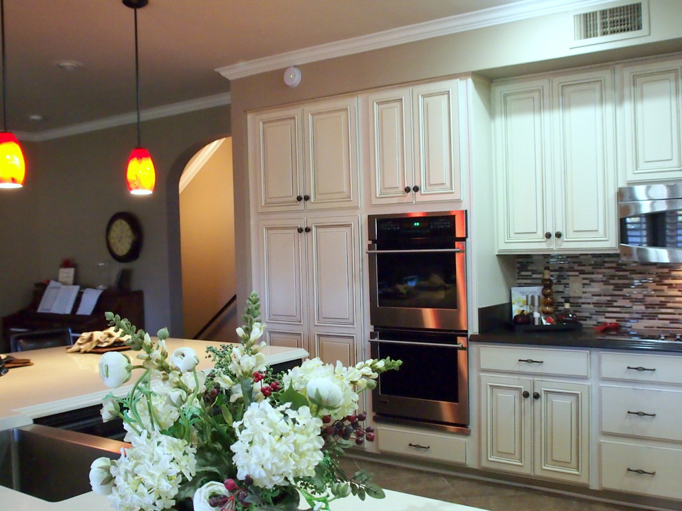 Large transitional cement tile floor and brown floor open concept kitchen photo in Phoenix with raised-panel cabinets, white cabinets, solid surface countertops, brown backsplash, matchstick tile backsplash, stainless steel appliances, an island and a farmhouse sink