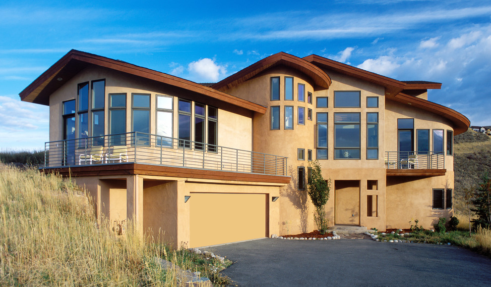 Large contemporary brown two-story stucco gable roof idea in Denver
