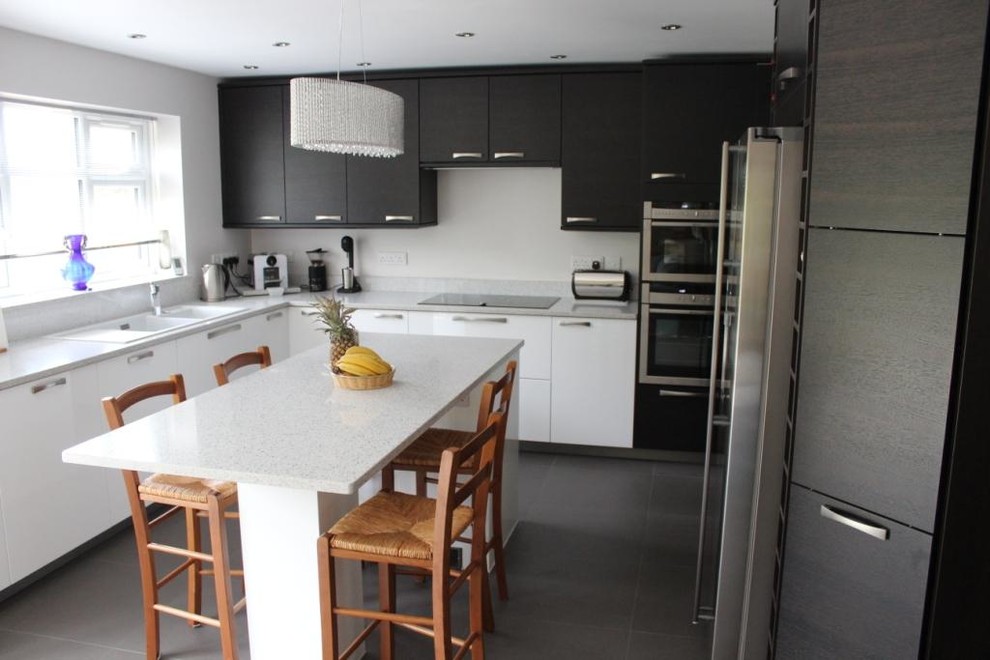 Exemple d'une cuisine américaine rétro en L de taille moyenne avec un évier 2 bacs, un placard sans porte, des portes de placard blanches, un plan de travail en quartz, un électroménager en acier inoxydable, un sol en carrelage de céramique, îlot, un sol gris, un plan de travail blanc et un plafond décaissé.
