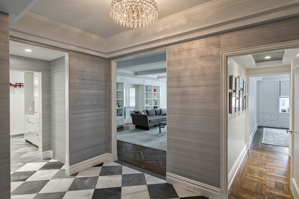This is an example of a mid-sized contemporary foyer in New York with grey walls, marble floors and a single front door.