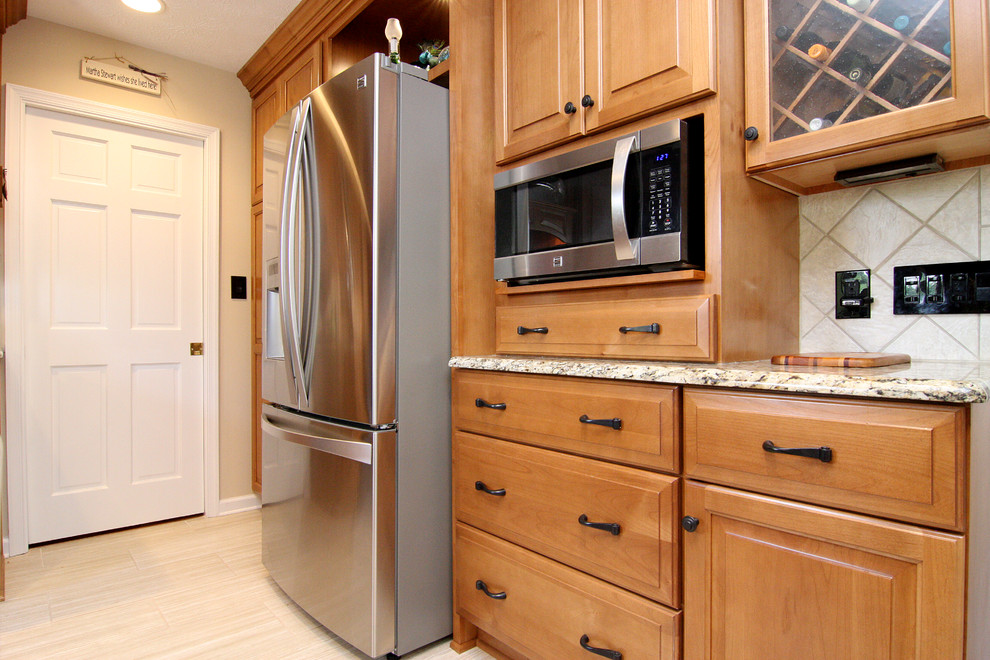 Example of a large transitional u-shaped porcelain tile eat-in kitchen design with an undermount sink, raised-panel cabinets, medium tone wood cabinets, granite countertops, beige backsplash, porcelain backsplash and stainless steel appliances