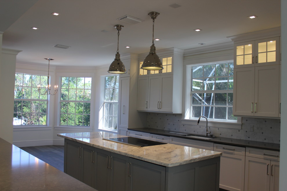 This is an example of a large transitional eat-in kitchen in Other with shaker cabinets, white cabinets, marble benchtops, grey splashback, stone tile splashback, panelled appliances, with island and grey floor.