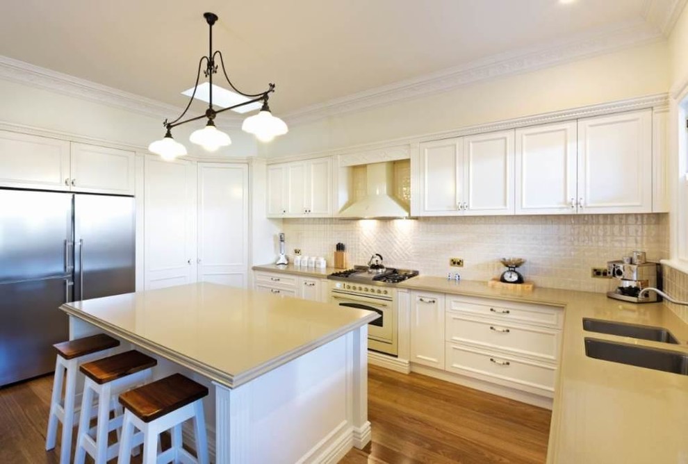 Inspiration for a country l-shaped eat-in kitchen in Melbourne with an undermount sink, shaker cabinets, white cabinets, soapstone benchtops, white splashback, porcelain splashback and white appliances.