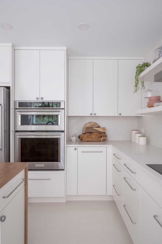 Inspiration for a small contemporary l-shaped kitchen in Vancouver with with island, flat-panel cabinets, white cabinets, white splashback, stainless steel appliances, white floor and white benchtop.