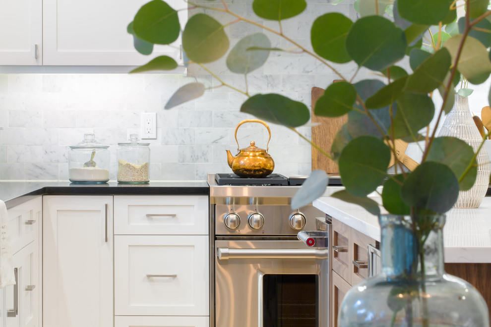 Eat-in kitchen - mid-sized transitional l-shaped light wood floor and brown floor eat-in kitchen idea in Seattle with an undermount sink, shaker cabinets, white cabinets, quartz countertops, multicolored backsplash, marble backsplash, stainless steel appliances and an island