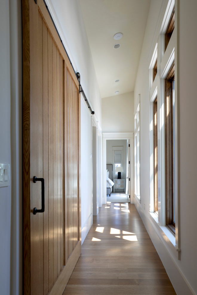 Photo of a large beach style hallway in Other with white walls, medium hardwood floors and brown floor.