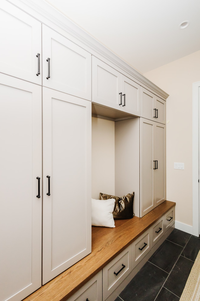 This is an example of a mid-sized country mudroom in Other with beige walls, ceramic floors, a single front door and black floor.