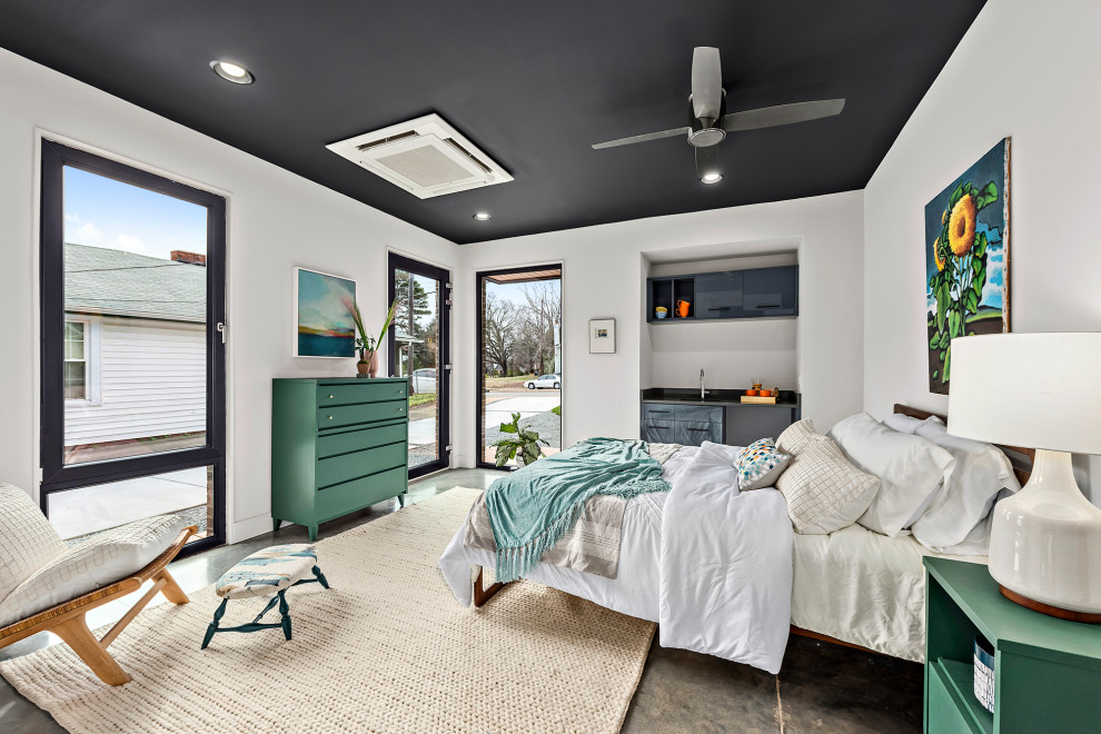 Mid-sized contemporary guest bedroom in Charlotte with white walls, concrete floors and grey floor.