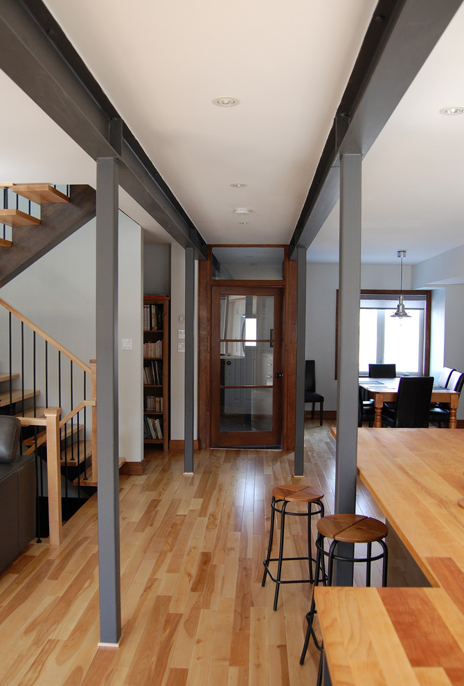 Inspiration for a mid-sized modern hallway in Montreal with white walls, light hardwood floors and exposed beam.