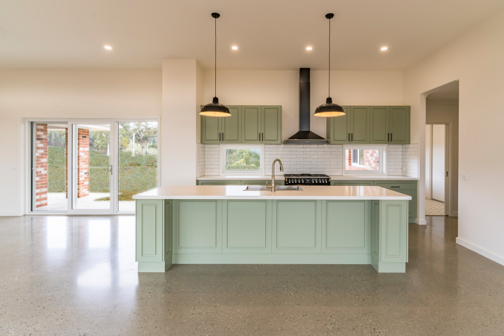 Large contemporary galley kitchen pantry in Other with a drop-in sink, recessed-panel cabinets, green cabinets, quartz benchtops, white splashback, ceramic splashback, black appliances, concrete floors, with island, grey floor and white benchtop.