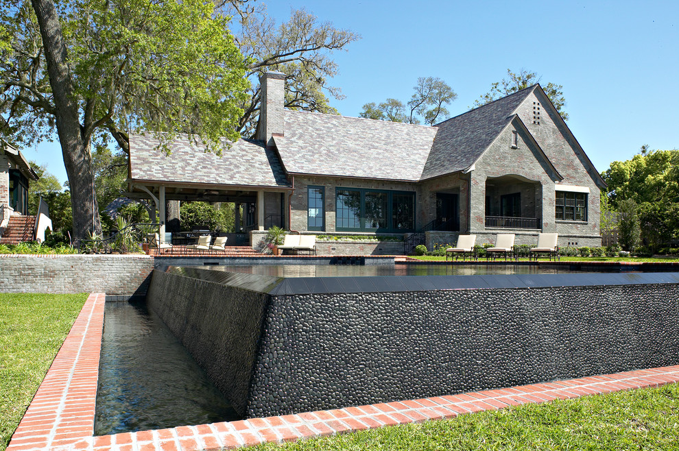 Design ideas for a backyard custom-shaped infinity pool in Jacksonville with a pool house and brick pavers.