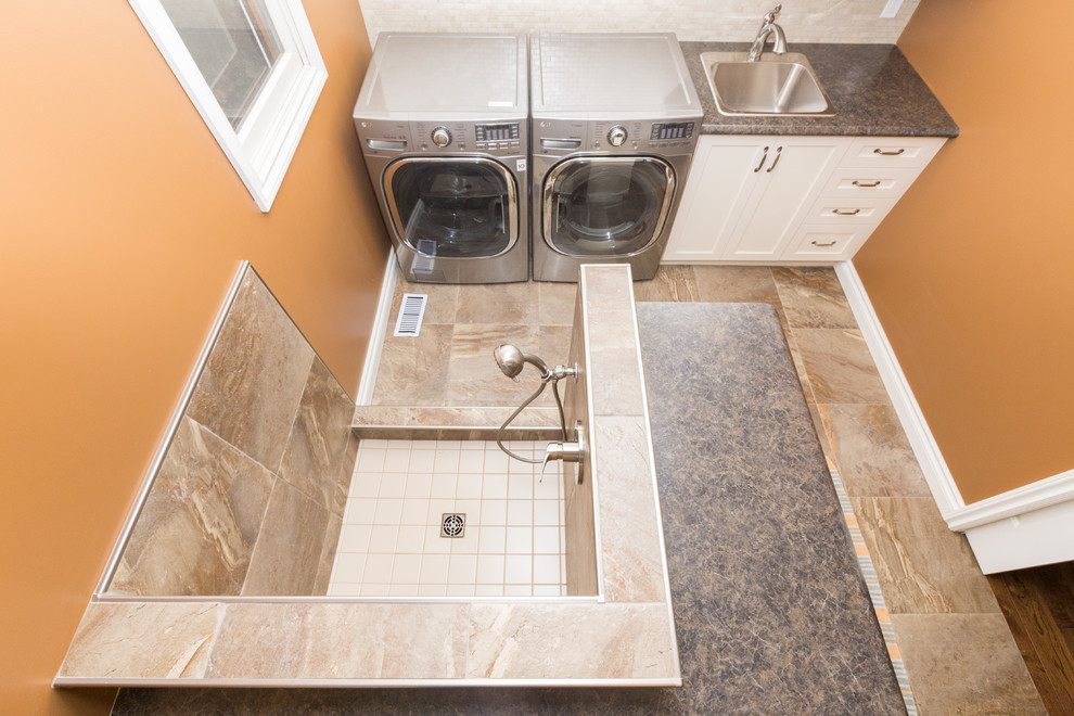 Mid-sized traditional galley utility room in Toronto with a drop-in sink, shaker cabinets, white cabinets, laminate benchtops, porcelain floors, a side-by-side washer and dryer, grey floor and orange walls.