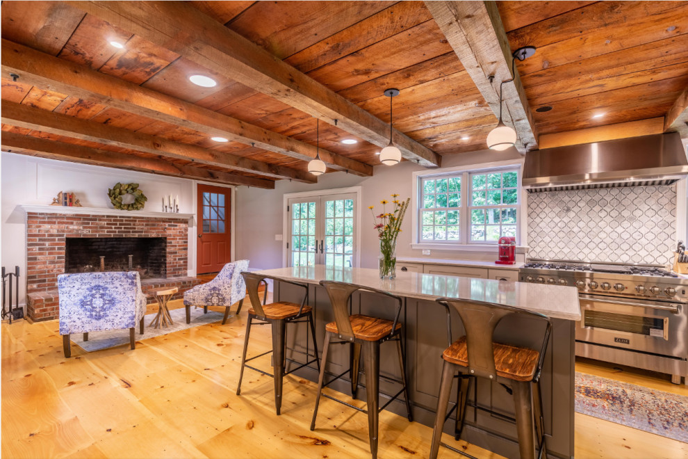 This is an example of a country galley kitchen in Boston with a farmhouse sink, stainless steel appliances, medium hardwood floors, multiple islands, white benchtop and wood.