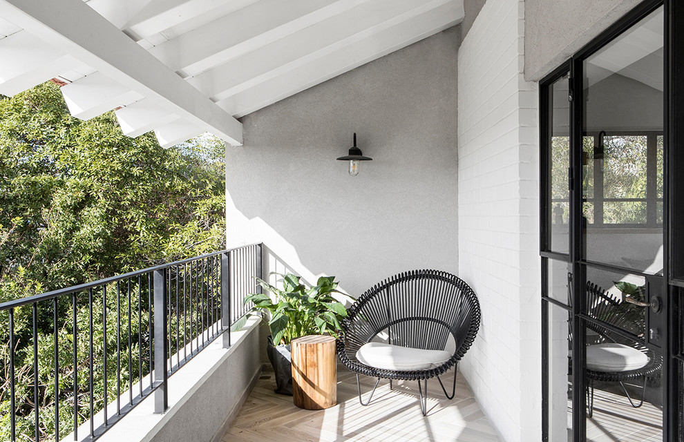 Large contemporary balcony in Los Angeles with a roof extension and metal railing.