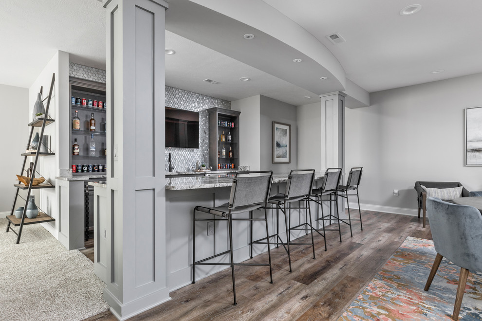 Design ideas for a transitional galley home bar in Indianapolis with open cabinets, grey cabinets, grey splashback, mosaic tile splashback, dark hardwood floors, brown floor and grey benchtop.