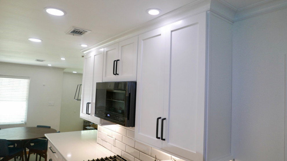 Inspiration for a mid-sized transitional galley porcelain tile and gray floor eat-in kitchen remodel with an undermount sink, shaker cabinets, white cabinets, quartz countertops, white backsplash, subway tile backsplash, black appliances, no island and white countertops