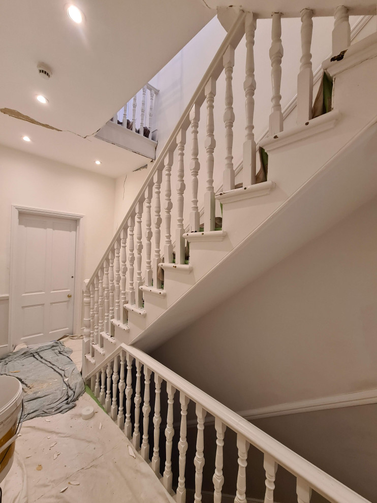This is an example of a large traditional hallway in London with beige walls, carpet, beige floor and coffered.