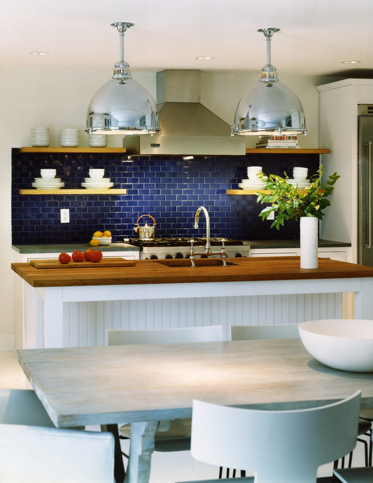 This is an example of a beach style galley eat-in kitchen in DC Metro with an undermount sink, blue splashback, subway tile splashback, stainless steel appliances and with island.
