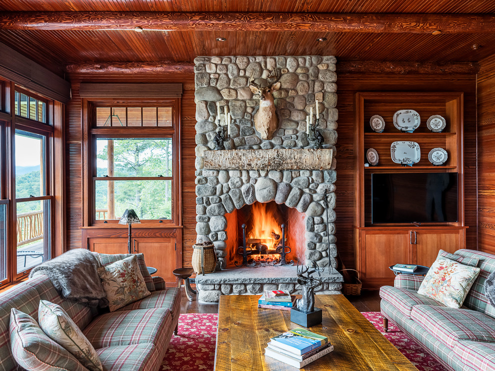 Inspiration for a country family room in Boston with brown walls, dark hardwood floors, a standard fireplace, a stone fireplace surround, a wall-mounted tv and brown floor.