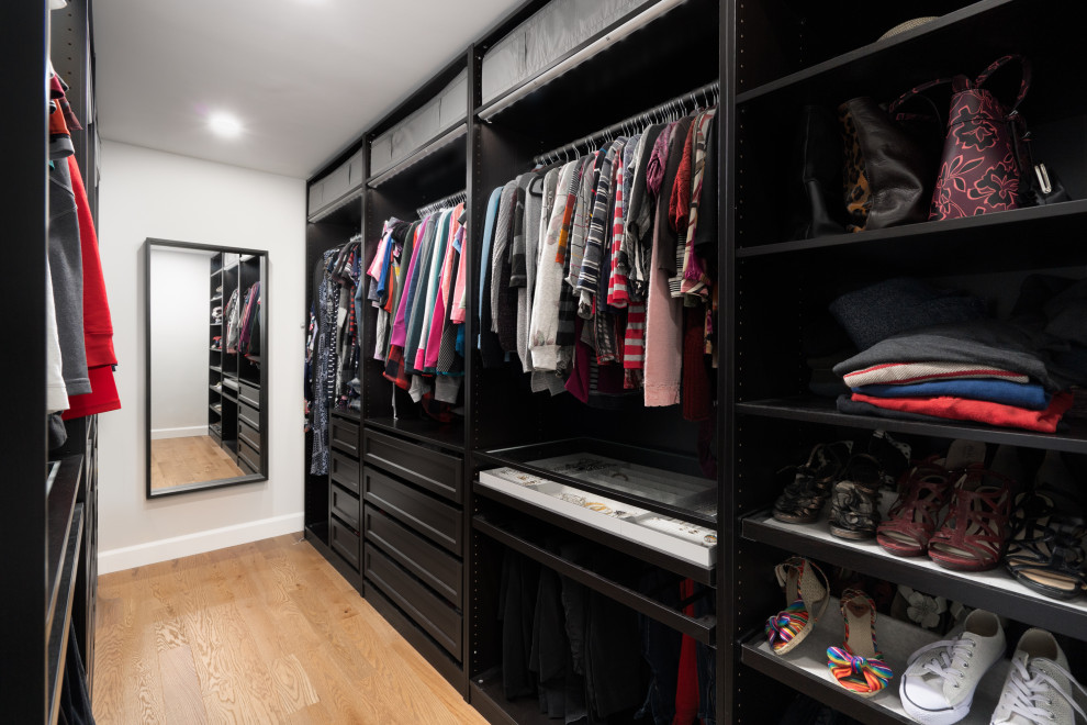 Photo of an expansive contemporary storage and wardrobe in Montreal with light hardwood floors, brown floor and vaulted.