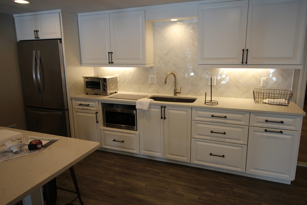 Eat-in kitchen - mid-sized transitional single-wall vinyl floor eat-in kitchen idea in Detroit with an undermount sink, raised-panel cabinets, white cabinets, quartz countertops, white backsplash, stone tile backsplash, stainless steel appliances and a peninsula