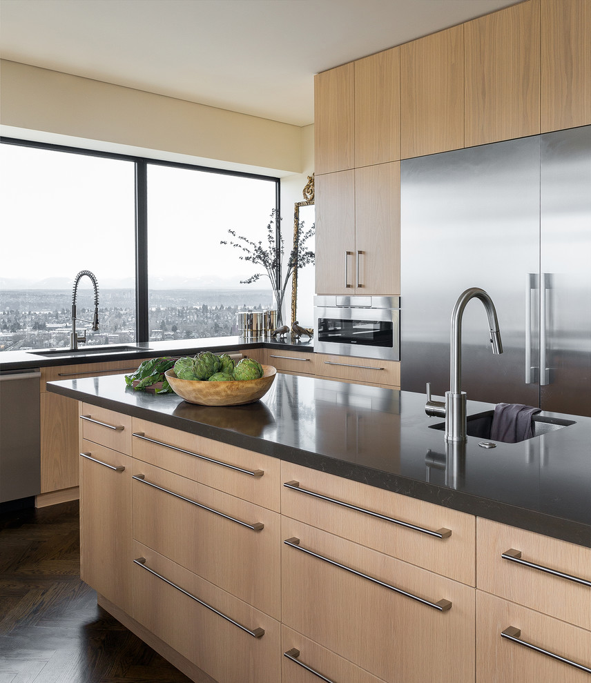 This is an example of a contemporary kitchen in Seattle with an undermount sink, flat-panel cabinets, light wood cabinets, solid surface benchtops, stainless steel appliances, grey benchtop, window splashback, dark hardwood floors and with island.