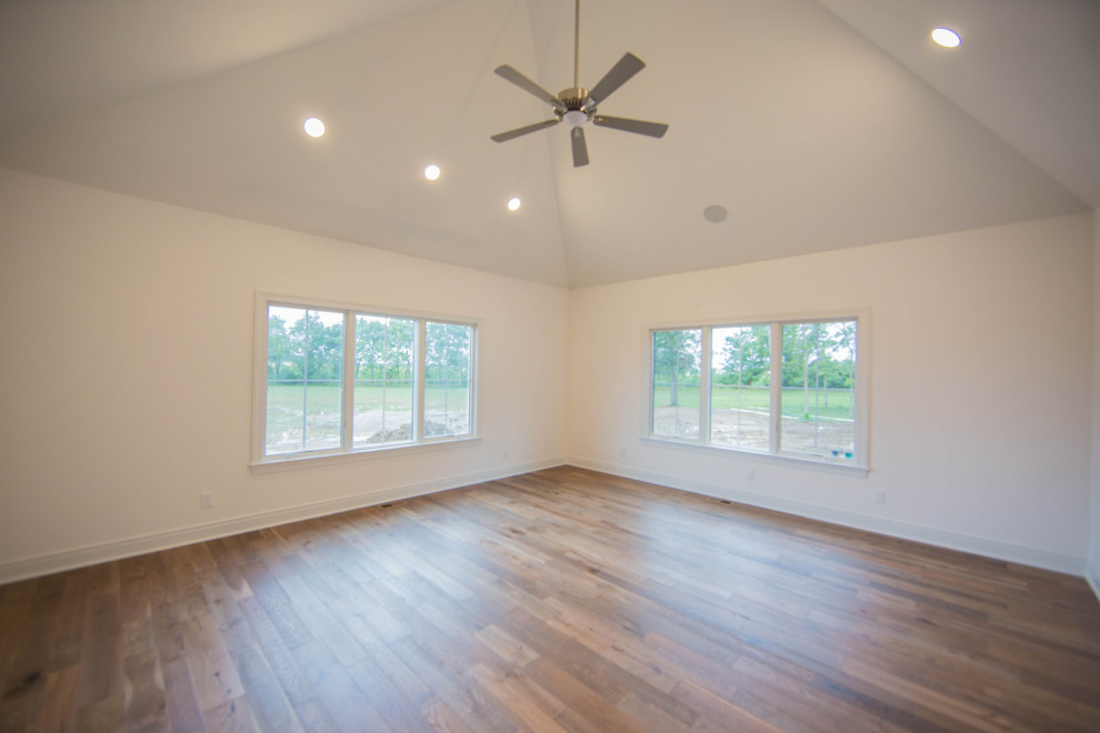 Expansive classic enclosed games room in Indianapolis with white walls, medium hardwood flooring, no fireplace, brown floors and a vaulted ceiling.