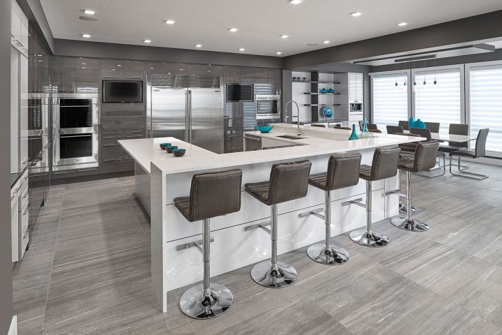 Photo of an expansive modern l-shaped eat-in kitchen in Edmonton with an undermount sink, flat-panel cabinets, grey cabinets, quartz benchtops, white splashback, ceramic splashback, stainless steel appliances, porcelain floors and with island.