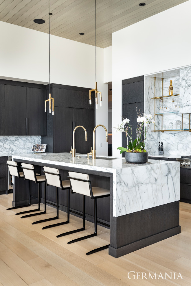 Design ideas for a modern u-shaped open plan kitchen in Salt Lake City with a drop-in sink, flat-panel cabinets, black cabinets, panelled appliances, light hardwood floors, with island, white benchtop and wood.