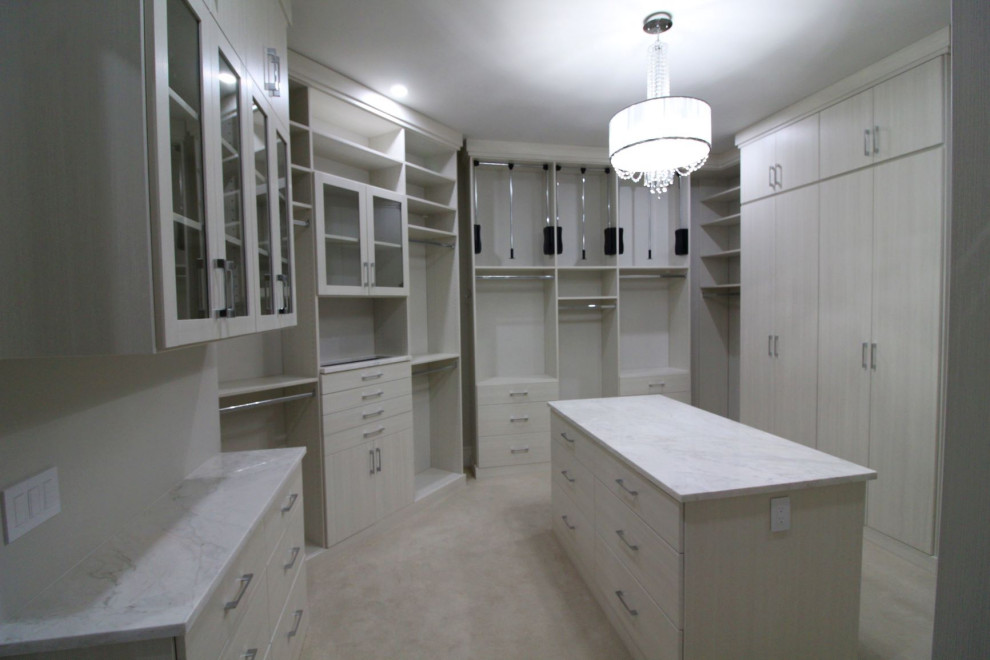 This is an example of a large transitional women's walk-in wardrobe in Indianapolis with glass-front cabinets, beige cabinets, carpet and beige floor.