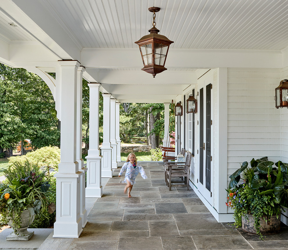 Inspiration for a country verandah in New York with natural stone pavers and a roof extension.