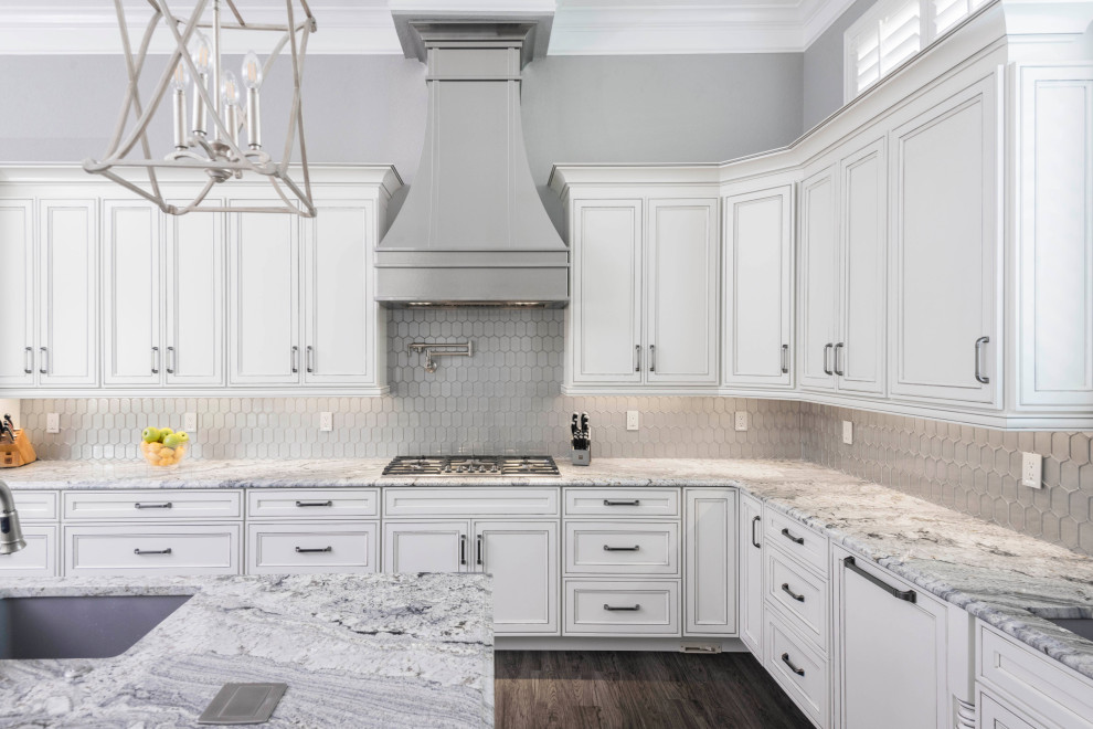 Kitchen - large transitional u-shaped laminate floor and multicolored floor kitchen idea in Orlando with an undermount sink, recessed-panel cabinets, white cabinets, granite countertops, metallic backsplash, glass tile backsplash, paneled appliances, an island and gray countertops