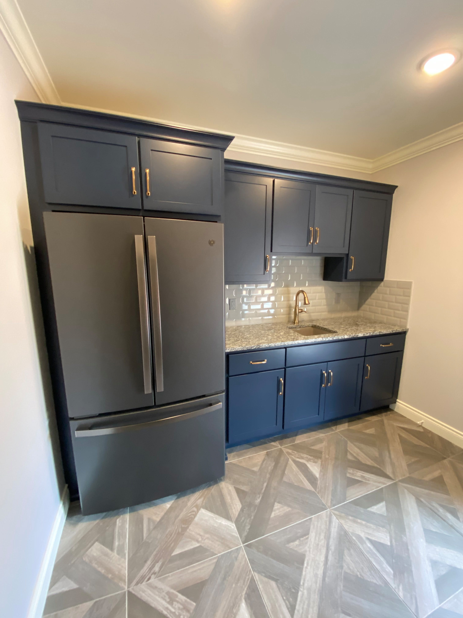 Basement kitchenette with custom painted cabinetry, subway tile, and granite cou