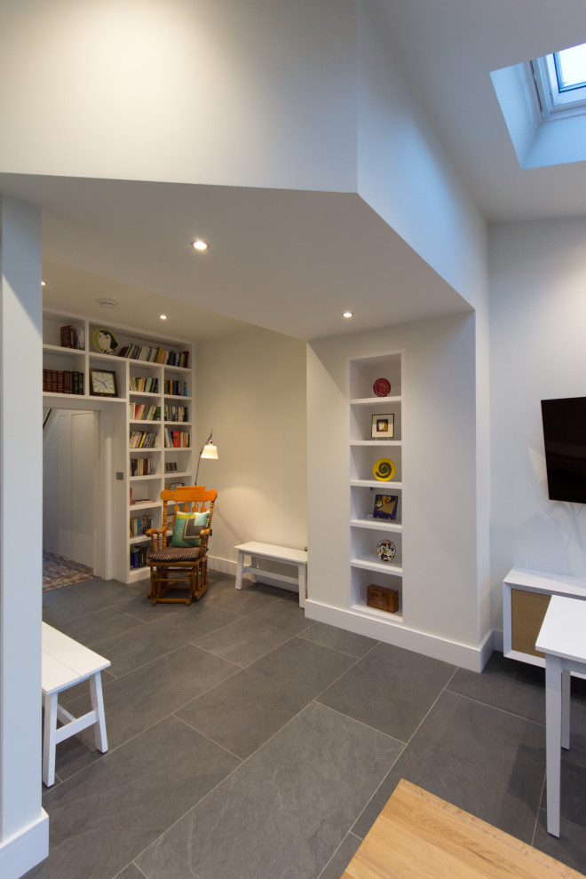This is an example of a mid-sized contemporary home office in London with a library, white walls, terra-cotta floors, no fireplace and multi-coloured floor.