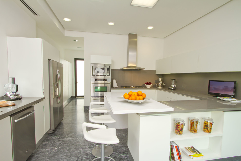 Photo of a contemporary u-shaped kitchen in Other with flat-panel cabinets, white cabinets, grey splashback and stainless steel appliances.