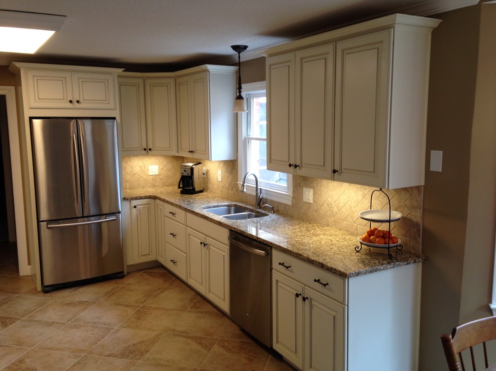 Example of a large classic galley porcelain tile eat-in kitchen design with an undermount sink, raised-panel cabinets, beige cabinets, granite countertops, beige backsplash, ceramic backsplash, stainless steel appliances and no island