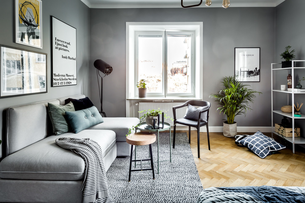 Scandinavian enclosed living room in Stockholm with grey walls, light hardwood floors and grey floor.