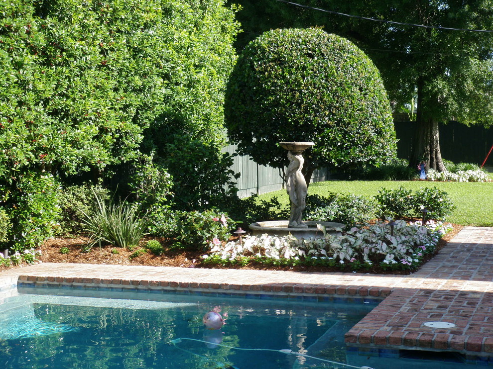 Traditional backyard garden in New Orleans with a water feature and brick pavers.