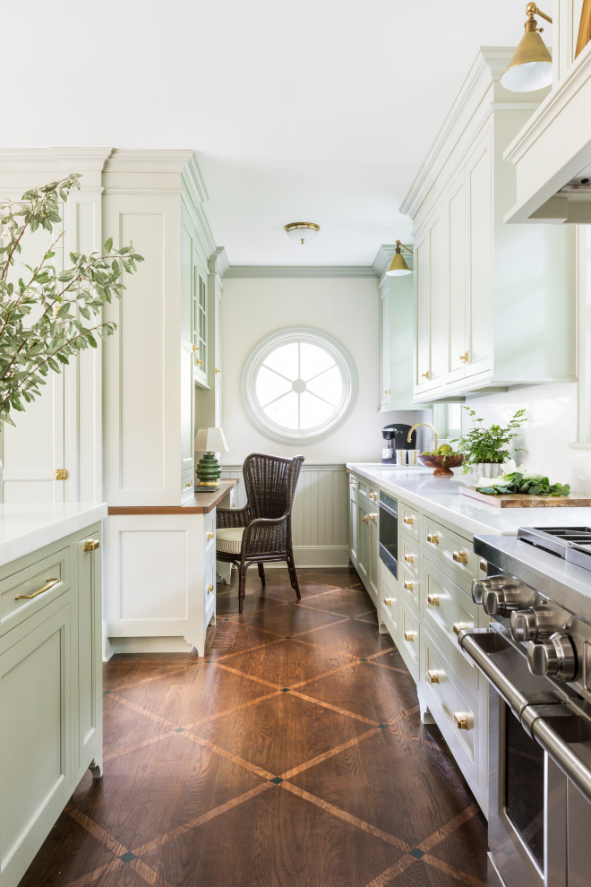 Large traditional single-wall eat-in kitchen in New York with a farmhouse sink, recessed-panel cabinets, beige cabinets, marble benchtops, white splashback, marble splashback, stainless steel appliances, dark hardwood floors, with island, brown floor and white benchtop.