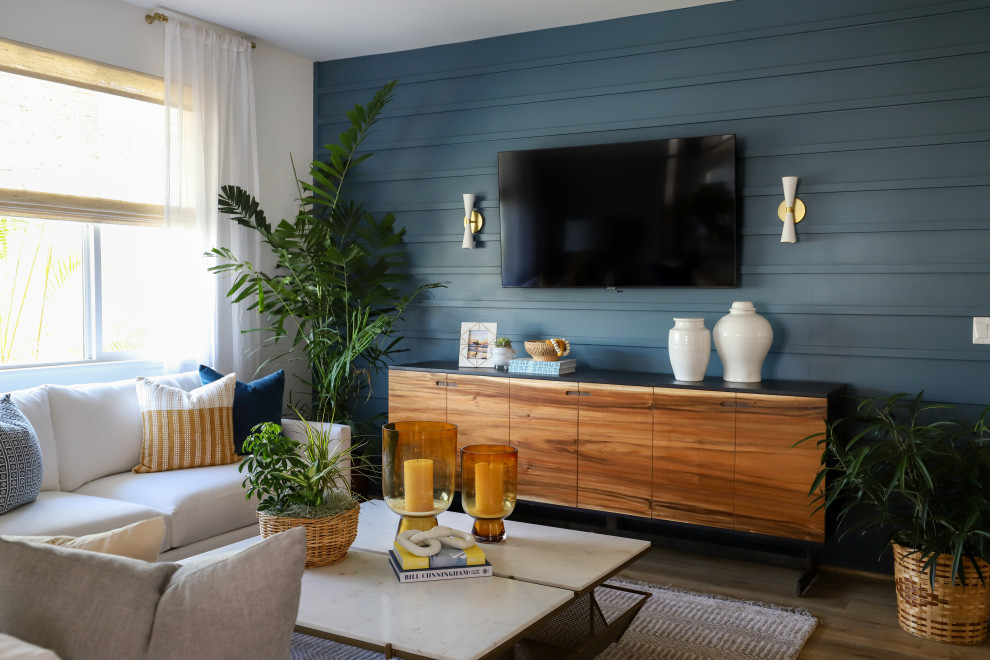 Modelo de sala de estar marinera pequeña con paredes azules, suelo de madera en tonos medios, televisor colgado en la pared, suelo marrón y panelado
