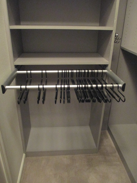 Photo of a small modern gender-neutral walk-in wardrobe in Los Angeles with flat-panel cabinets, grey cabinets, carpet and beige floor.