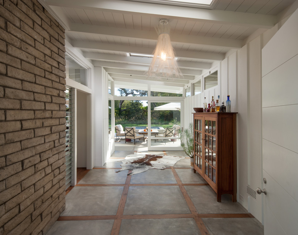 This is an example of a midcentury entryway in Santa Barbara with concrete floors.