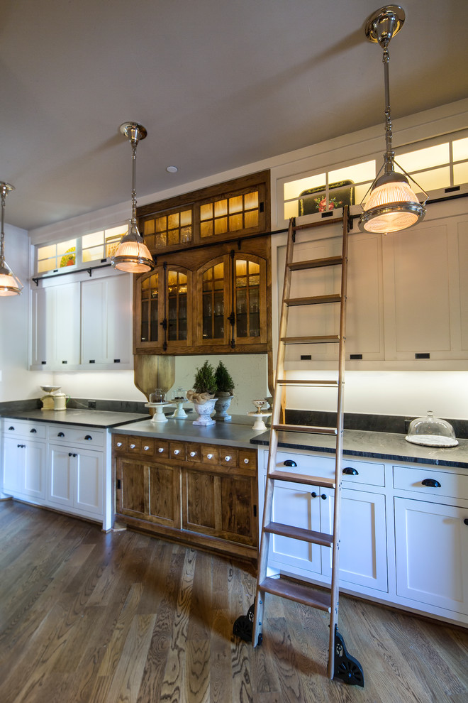 This is an example of a mid-sized country single-wall open plan kitchen in Dallas with an undermount sink, raised-panel cabinets, white cabinets, granite benchtops, white splashback, ceramic splashback, panelled appliances, medium hardwood floors and with island.