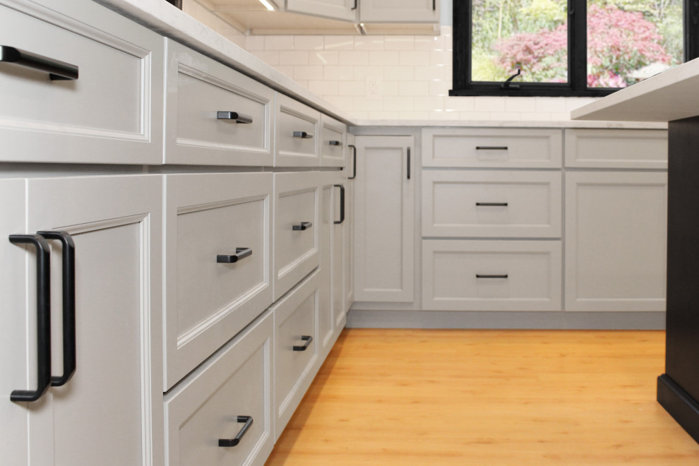 Enclosed kitchen - large transitional u-shaped light wood floor and brown floor enclosed kitchen idea in Boston with a double-bowl sink, shaker cabinets, gray cabinets, quartz countertops, white backsplash, porcelain backsplash, black appliances, an island and white countertops