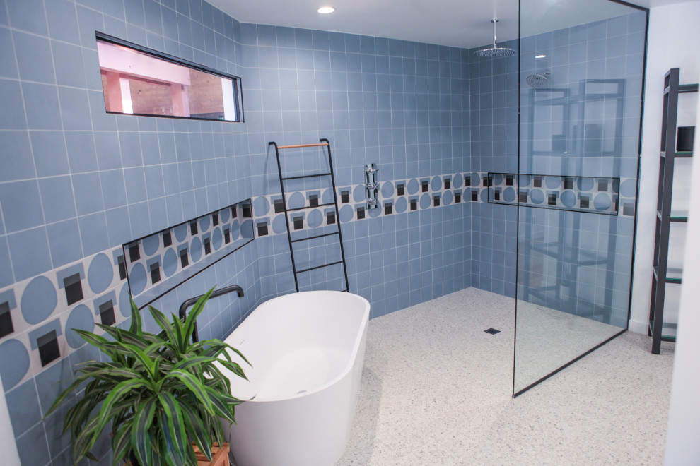 This is an example of a mid-sized modern master bathroom in Los Angeles with open cabinets, brown cabinets, a freestanding tub, a curbless shower, a one-piece toilet, blue tile, subway tile, white walls, terrazzo floors, a wall-mount sink, yellow floor and an open shower.