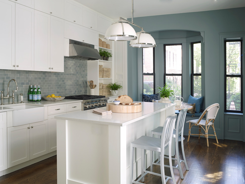 Design ideas for a mid-sized traditional u-shaped eat-in kitchen in New York with a farmhouse sink, recessed-panel cabinets, white cabinets, quartzite benchtops, blue splashback, subway tile splashback, stainless steel appliances, dark hardwood floors, with island, white benchtop and brown floor.